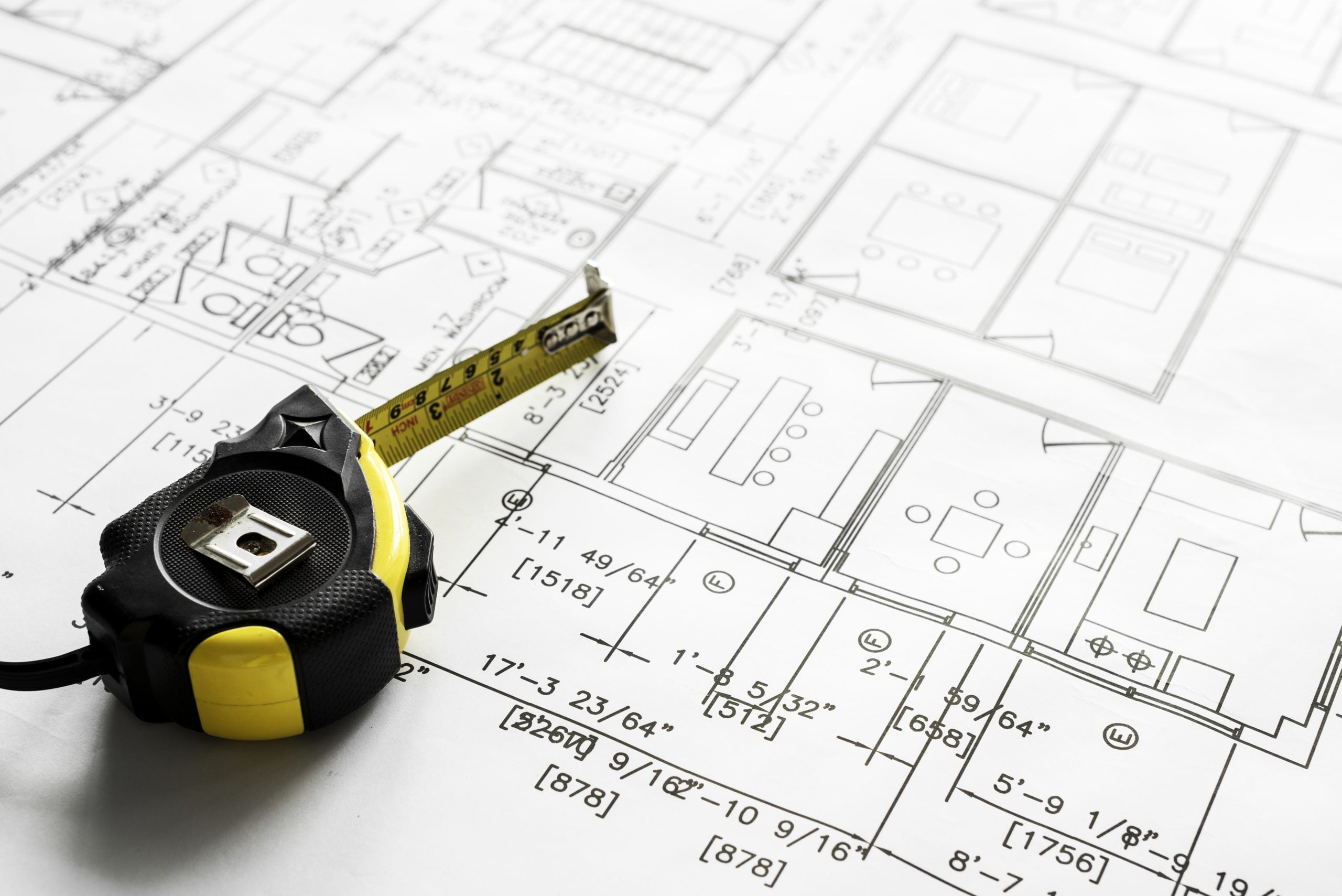 Closeup of house blueprints on table and measuring tape on top